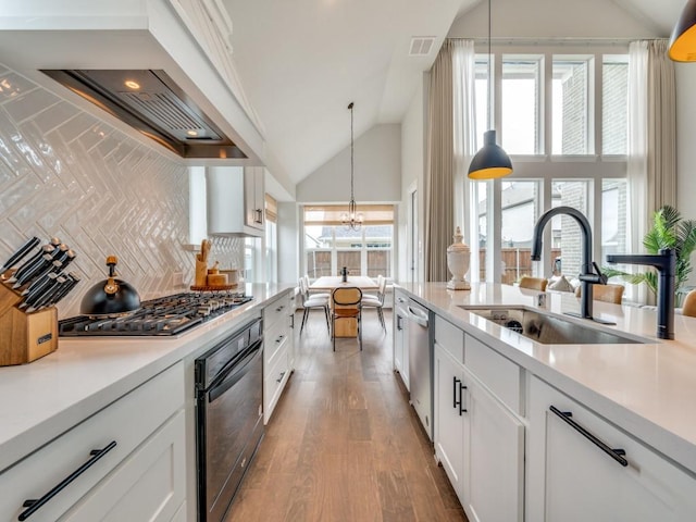kitchen featuring appliances with stainless steel finishes, a sink, light countertops, an inviting chandelier, and white cabinetry
