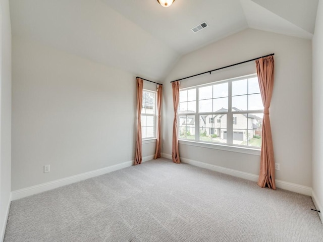 carpeted spare room featuring visible vents, baseboards, and lofted ceiling