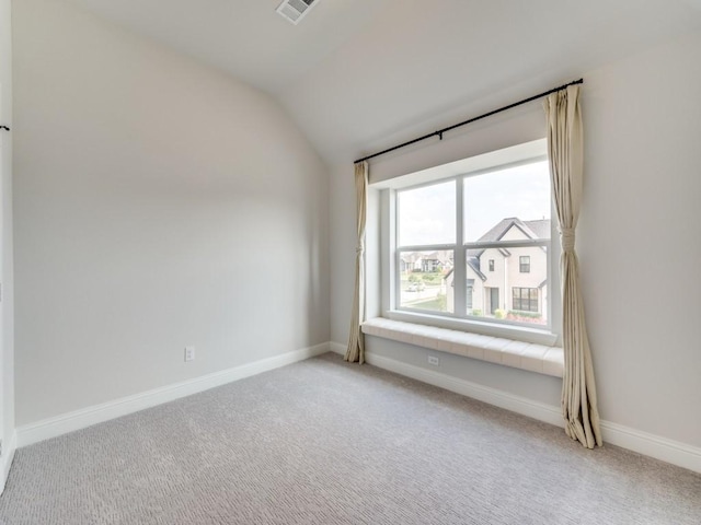 spare room with light colored carpet, baseboards, visible vents, and vaulted ceiling
