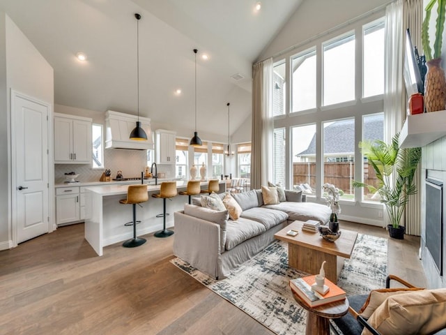 living area with recessed lighting, high vaulted ceiling, plenty of natural light, and light wood-type flooring
