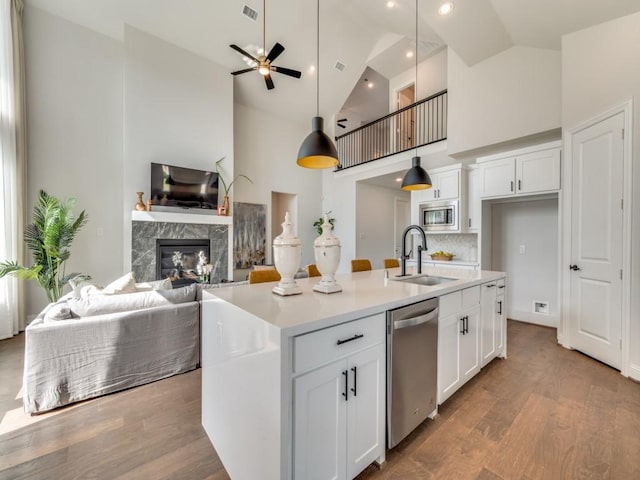 kitchen featuring visible vents, high vaulted ceiling, a sink, appliances with stainless steel finishes, and a premium fireplace