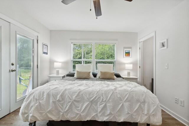 bedroom featuring access to outside, ceiling fan, multiple windows, and wood finished floors