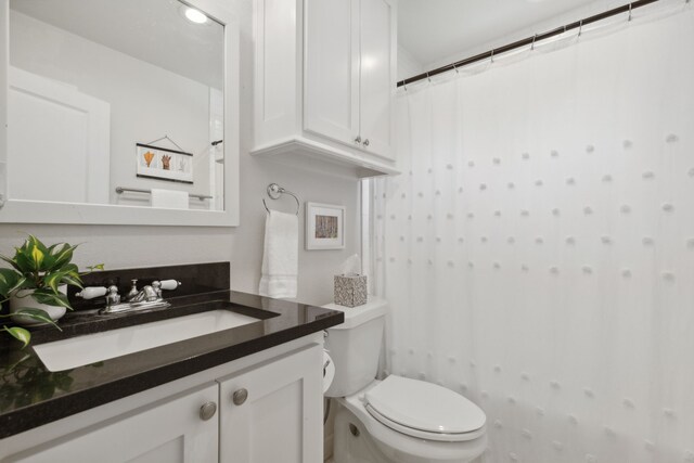 full bath featuring toilet, curtained shower, and vanity