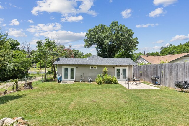 rear view of property featuring a lawn, french doors, and a fenced backyard