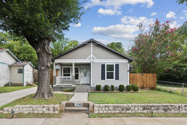 bungalow-style home featuring a porch, fence, and a front yard