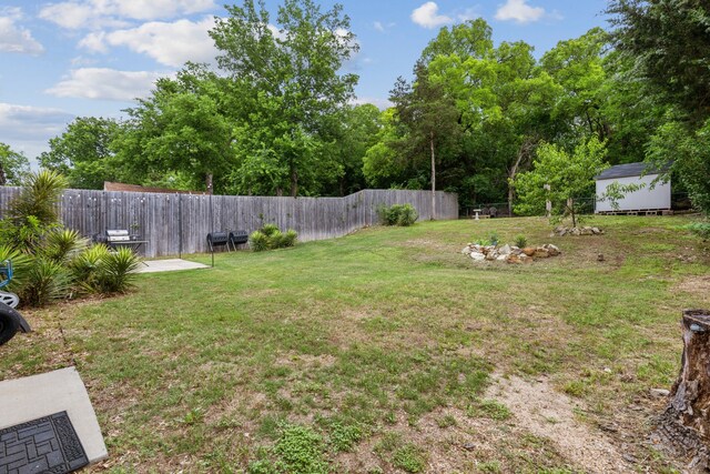 view of yard featuring a fenced backyard, a storage unit, and an outdoor structure