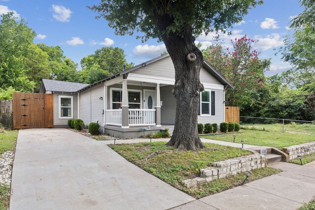 bungalow with fence, a front yard, a gate, covered porch, and driveway