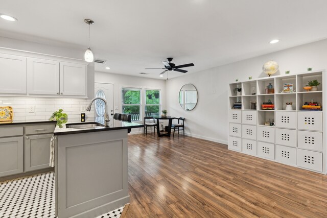 kitchen with dark countertops, ceiling fan, a sink, wood finished floors, and gray cabinetry