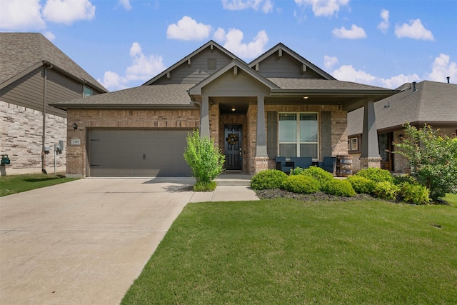 craftsman-style house featuring covered porch, a front yard, brick siding, an attached garage, and driveway