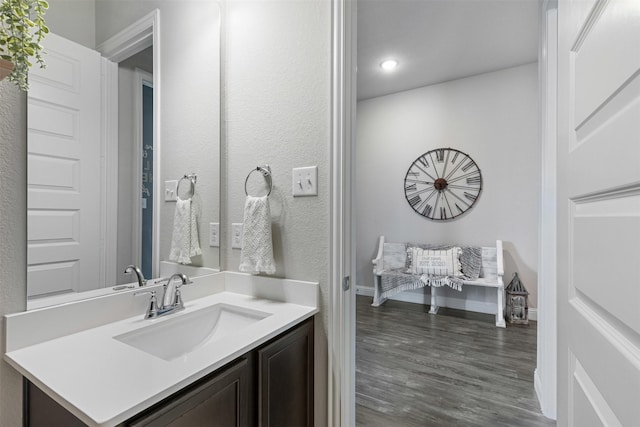 bathroom featuring recessed lighting, baseboards, wood finished floors, and vanity