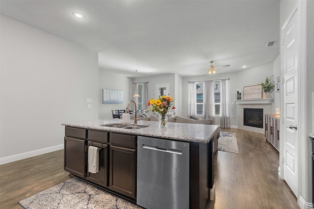 kitchen with dark wood-style flooring, a tile fireplace, dishwasher, a sink, and open floor plan