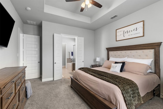 bedroom featuring a tray ceiling, visible vents, light carpet, and baseboards