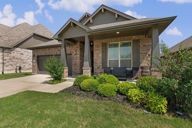 craftsman-style house with a porch, driveway, roof with shingles, brick siding, and an attached garage
