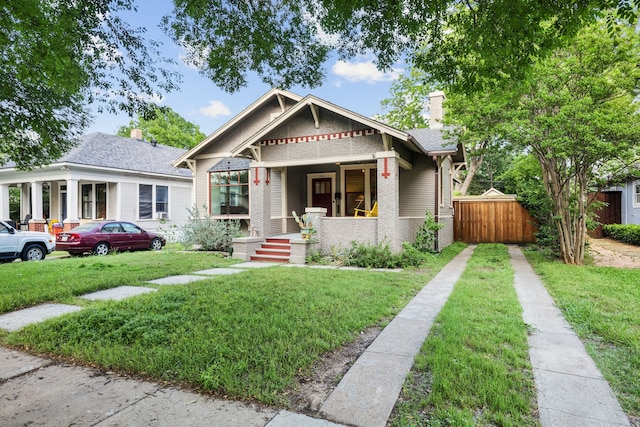 906 N Clinton Ave, Dallas, TX 75208 - view of front facade with a porch, fence, a front yard, and a chimney