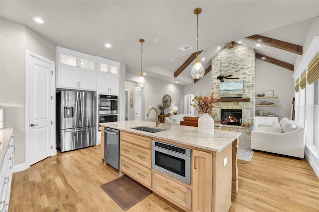 kitchen with a sink, appliances with stainless steel finishes, lofted ceiling with beams, and light wood finished floors