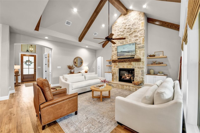 living room featuring light wood finished floors, a fireplace, arched walkways, recessed lighting, and beamed ceiling