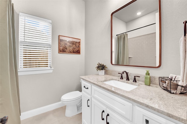 bathroom featuring toilet, baseboards, plenty of natural light, and vanity
