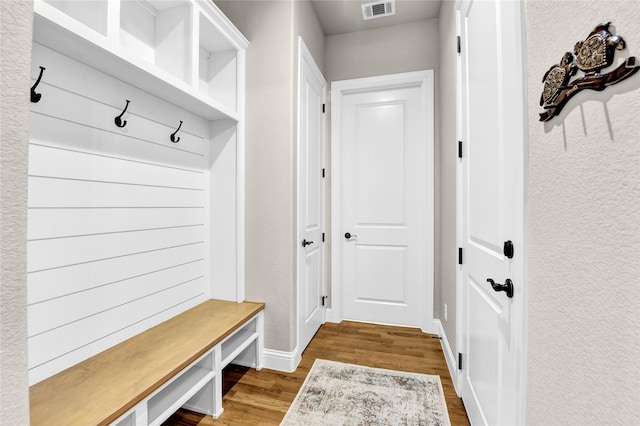 mudroom featuring baseboards, visible vents, and wood finished floors