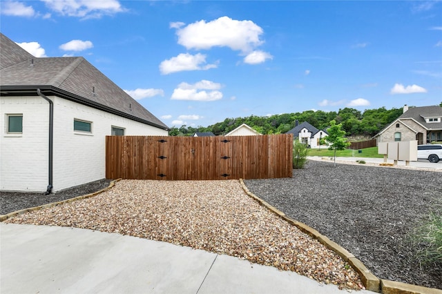 view of side of property with brick siding, a gate, and fence