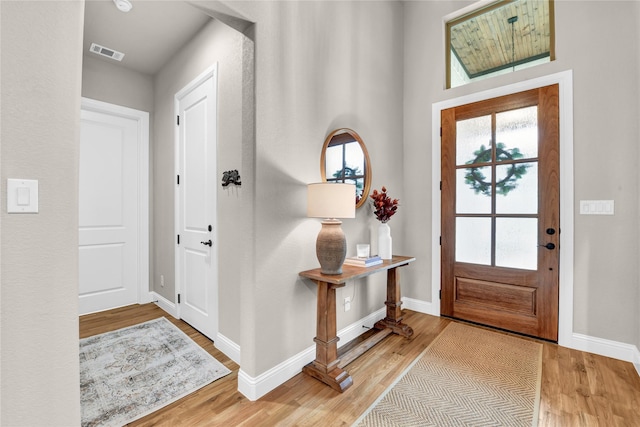 foyer entrance featuring baseboards, wood finished floors, and visible vents