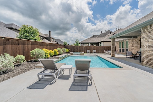 view of pool featuring a fenced backyard, a pool with connected hot tub, and a patio area