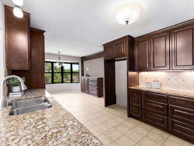 kitchen featuring a sink, decorative light fixtures, dark brown cabinets, and tasteful backsplash