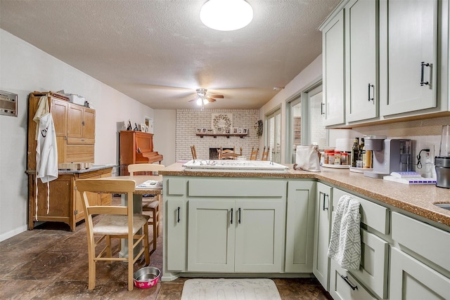 kitchen with a ceiling fan, a textured ceiling, white stovetop, a peninsula, and green cabinetry