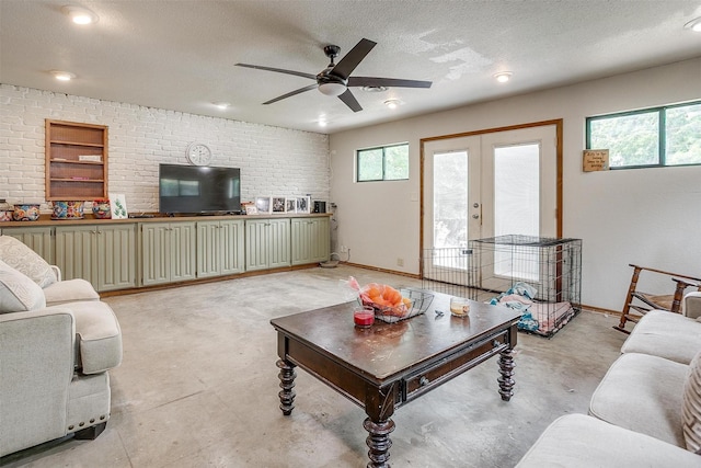 living area featuring french doors, a textured ceiling, ceiling fan, and a healthy amount of sunlight
