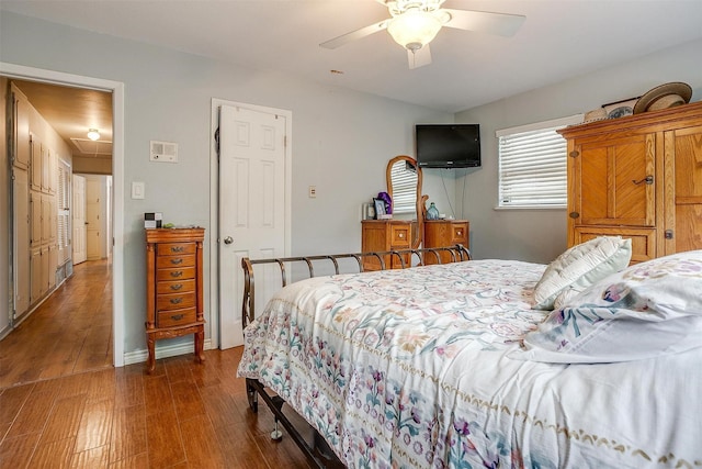 bedroom with a ceiling fan, attic access, and dark wood-style flooring