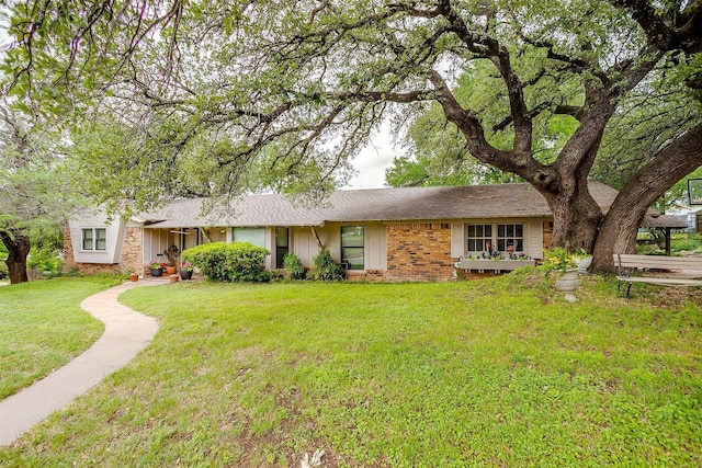 ranch-style house featuring a shingled roof and a front lawn