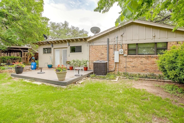 rear view of house featuring a yard, central AC, a deck, and brick siding