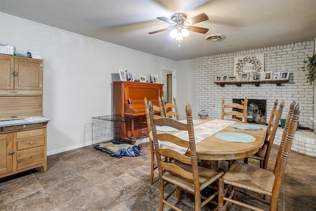 dining space with visible vents, a fireplace, baseboards, ceiling fan, and a textured ceiling