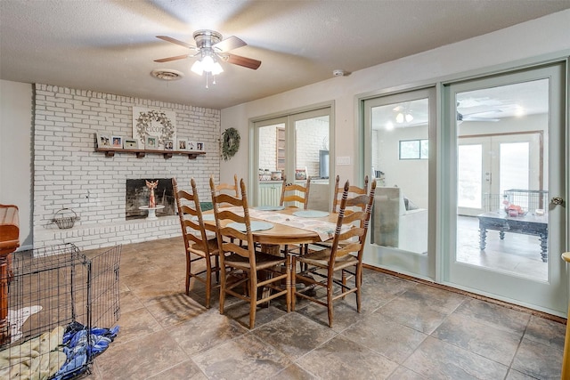 dining room featuring a ceiling fan, a textured ceiling, visible vents, and a fireplace
