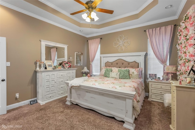 carpeted bedroom with crown molding, a raised ceiling, baseboards, and a ceiling fan