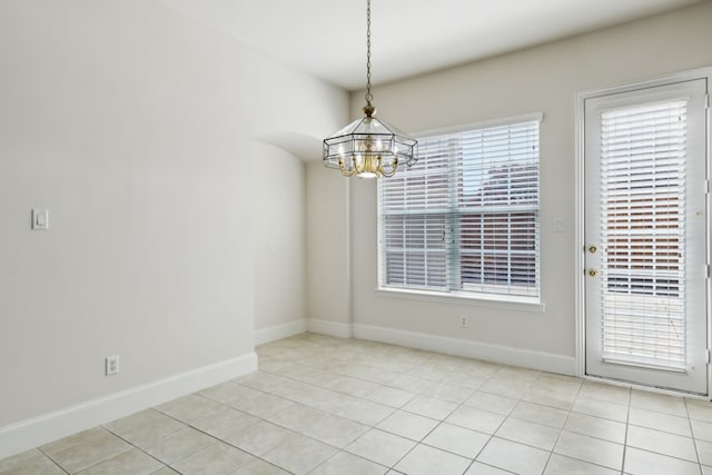 unfurnished dining area with baseboards, light tile patterned flooring, and a chandelier