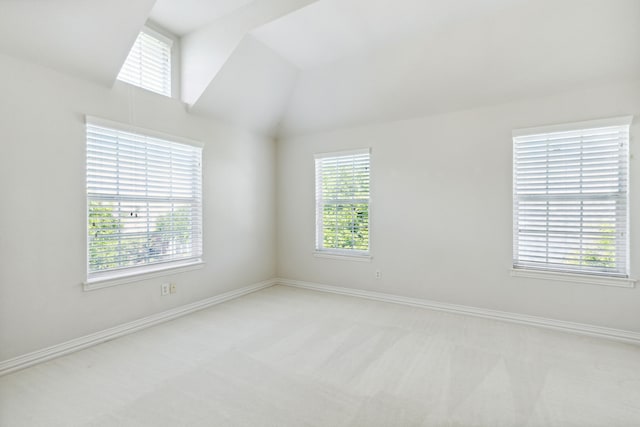 empty room with baseboards, lofted ceiling, and light carpet