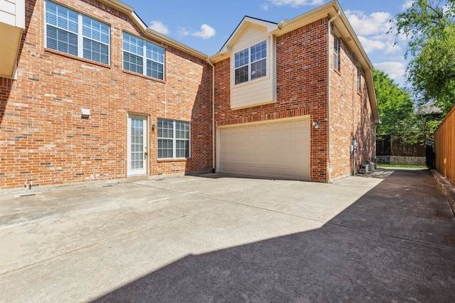 rear view of house featuring an attached garage, driveway, and brick siding