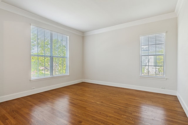 unfurnished room featuring a healthy amount of sunlight, baseboards, ornamental molding, and wood finished floors