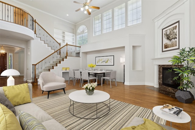 living room with wood finished floors, baseboards, ceiling fan, a high ceiling, and stairway