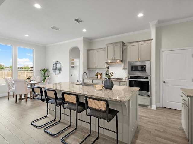 kitchen with stainless steel appliances, gray cabinetry, visible vents, and a sink