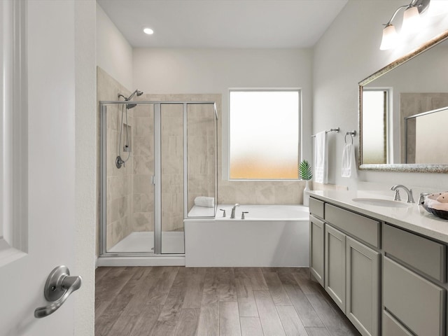 full bath featuring vanity, a bath, a shower stall, and wood finished floors