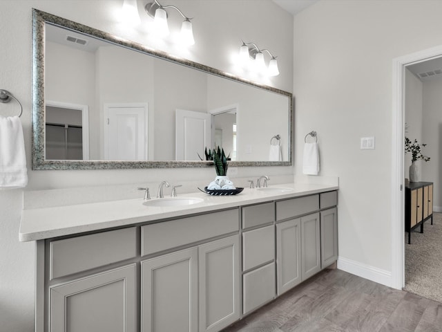 full bathroom with a sink, wood finished floors, double vanity, and visible vents