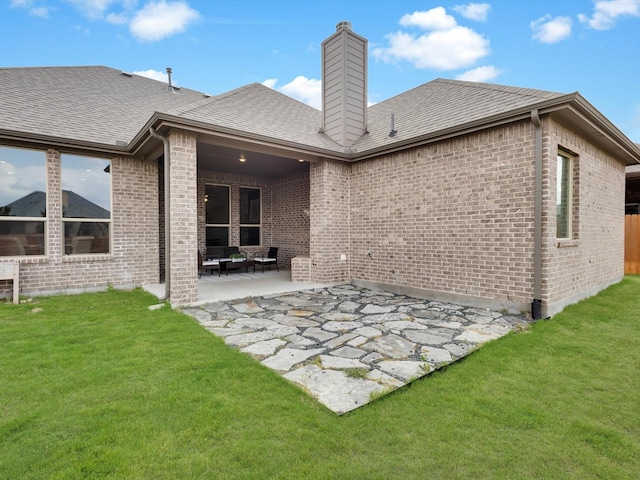 back of property with a lawn, a patio, a chimney, and brick siding