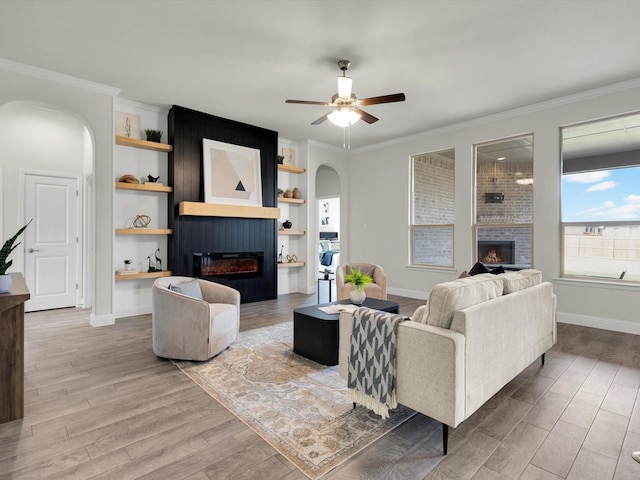 living area featuring arched walkways, wood finished floors, and a large fireplace