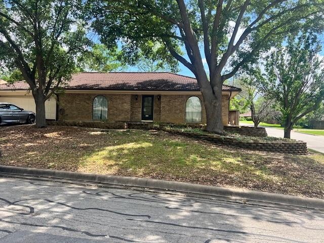 single story home featuring a tiled roof and brick siding