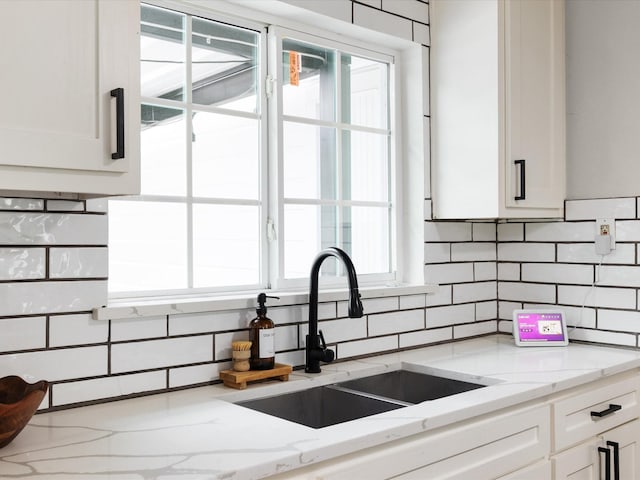 1821 Melissa St, Arlington, TX 76010 - kitchen featuring a sink, light stone countertops, backsplash, and white cabinetry