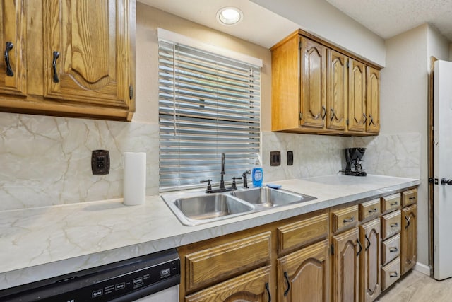 kitchen featuring white dishwasher, a sink, brown cabinets, and light countertops