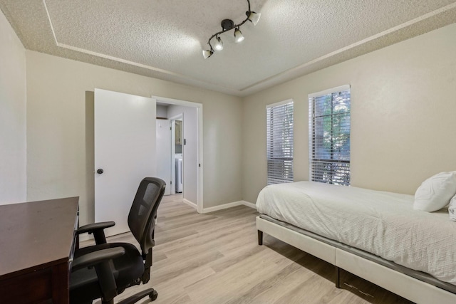 bedroom featuring baseboards, a textured ceiling, and light wood-style flooring