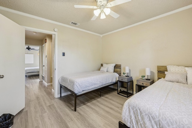 bedroom with visible vents, crown molding, ceiling fan, a textured ceiling, and light wood-style flooring
