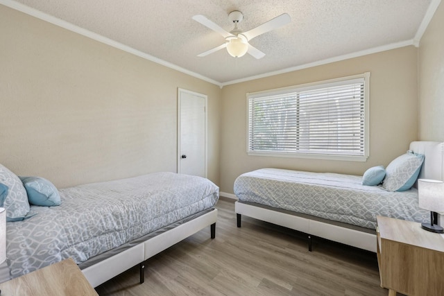 bedroom with a textured ceiling, ceiling fan, ornamental molding, and wood finished floors